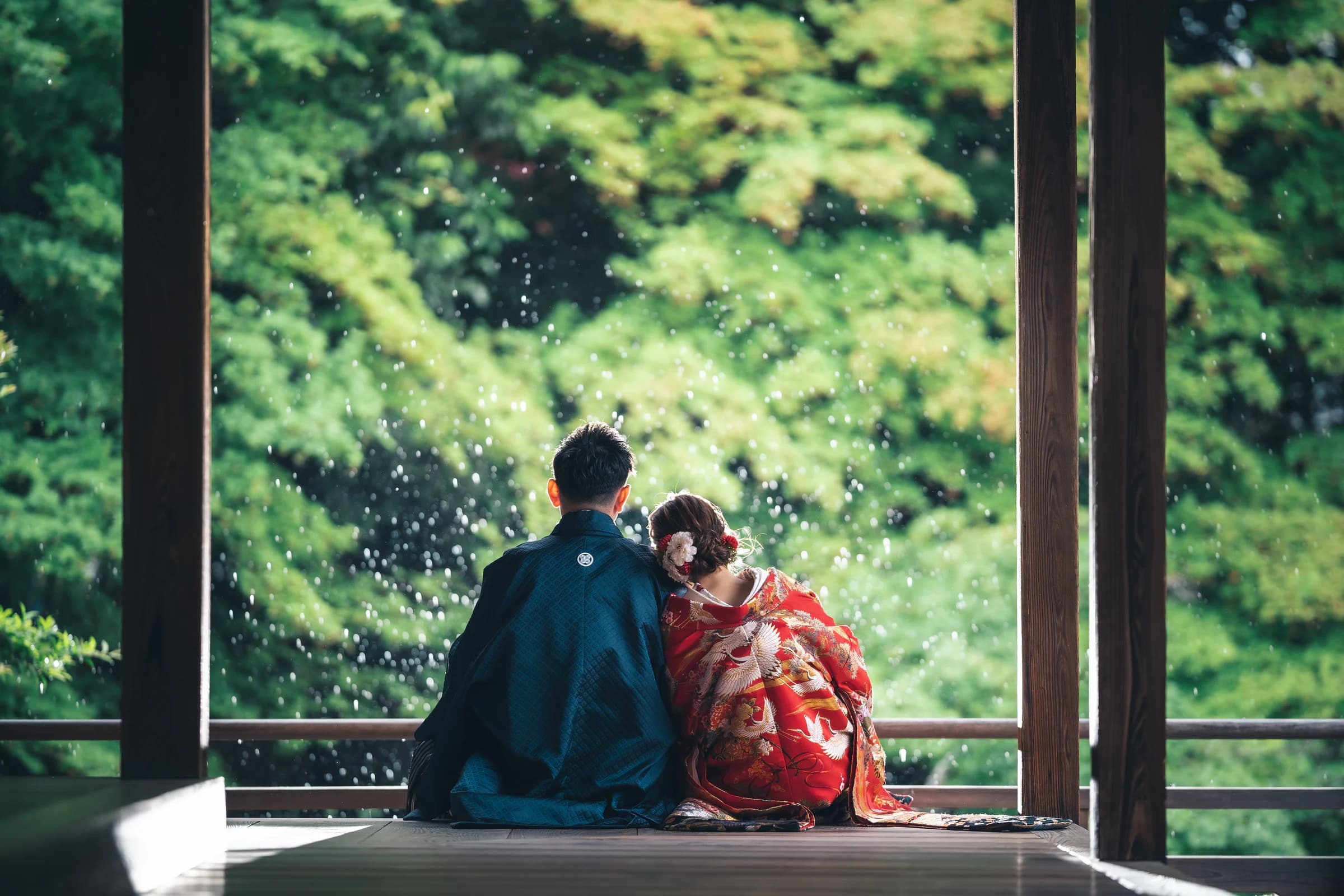 緑を背景に、水滴の中で並ぶ色打掛と黒紋付袴の新郎新婦