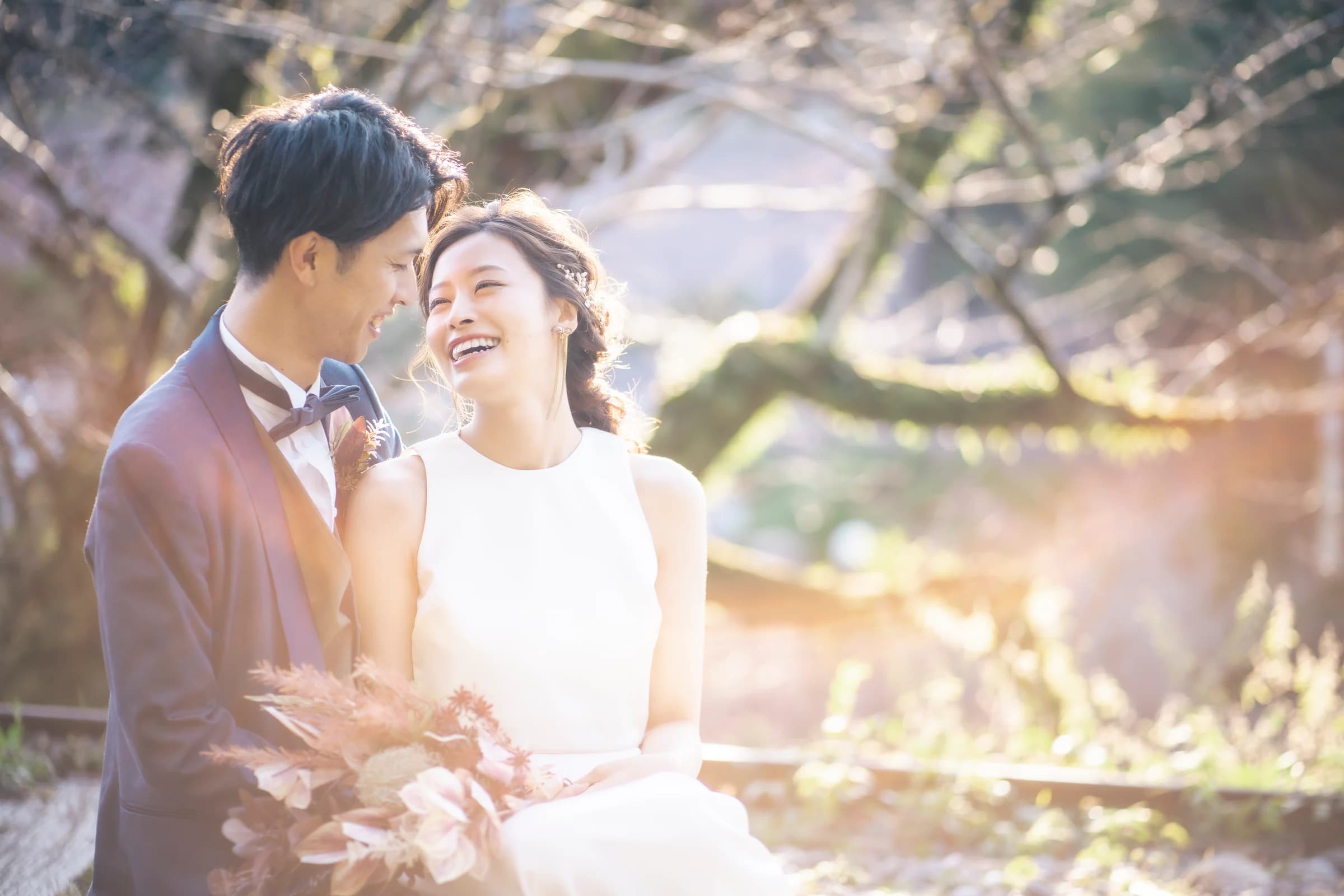 光の中で笑顔を交わすドレス姿の新婦と新郎