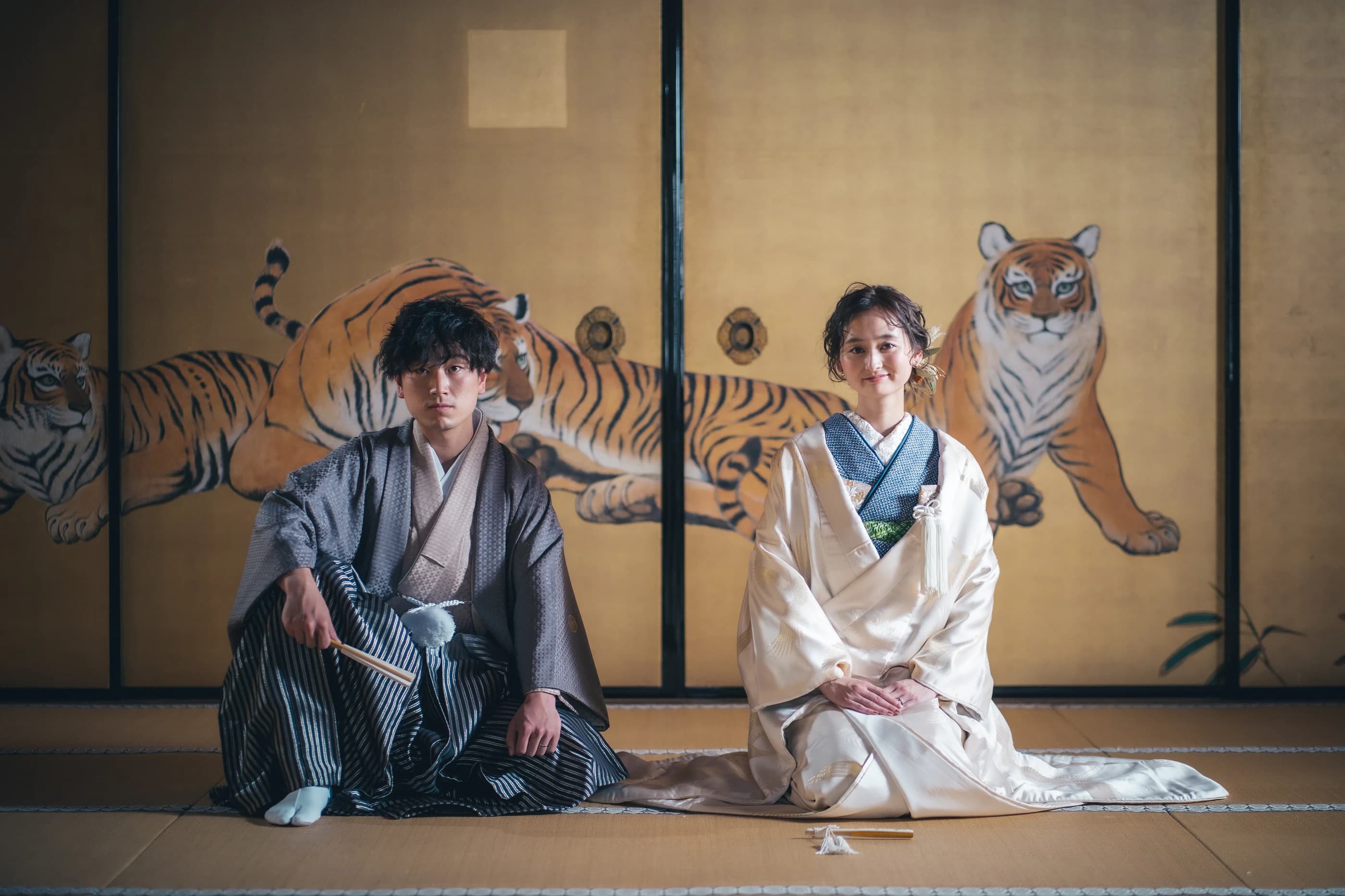 虎の襖絵の前で正座する和装の新郎新婦