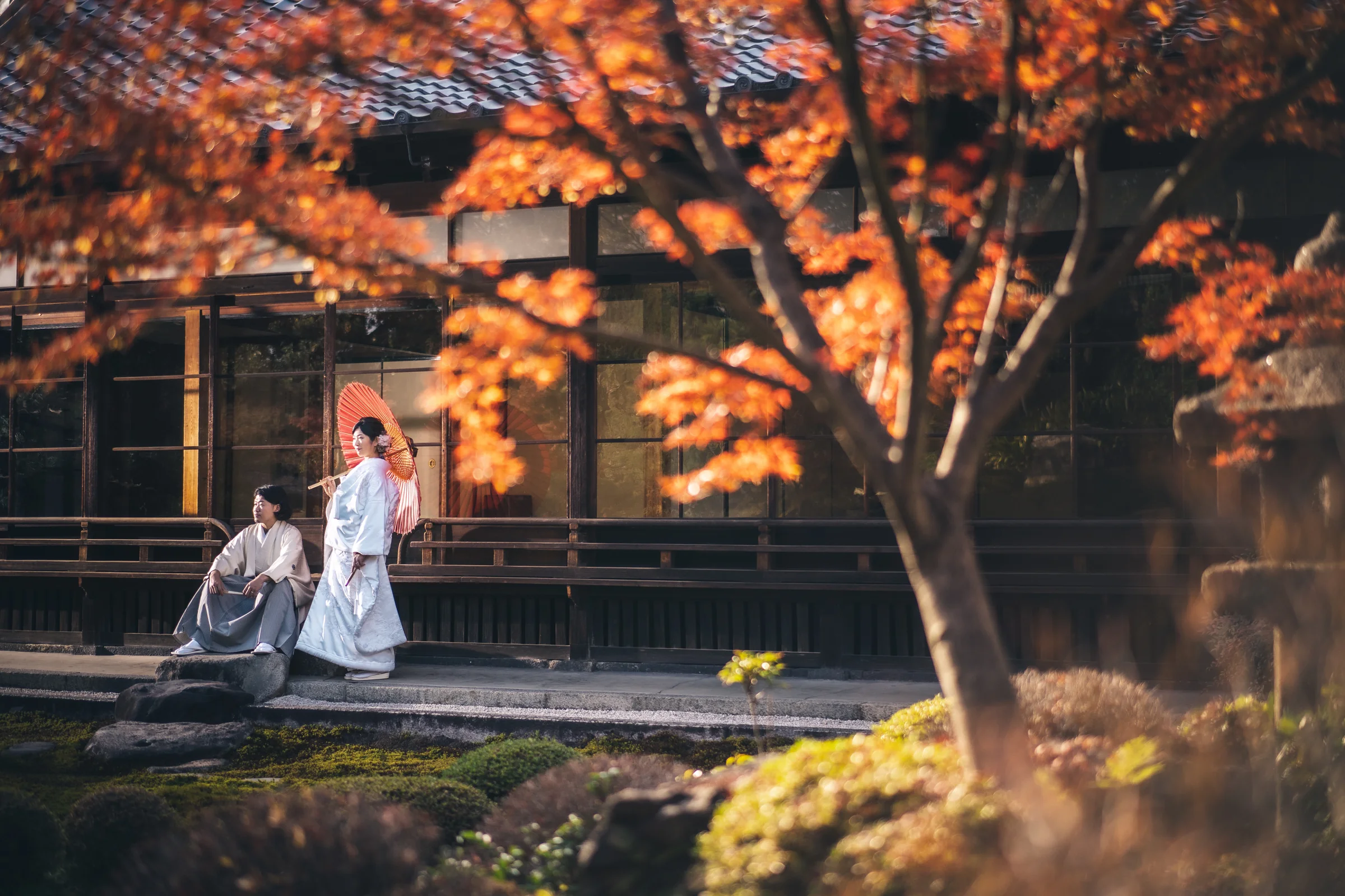 紅葉の庭と京都らしい建築の中に佇む和装の二人