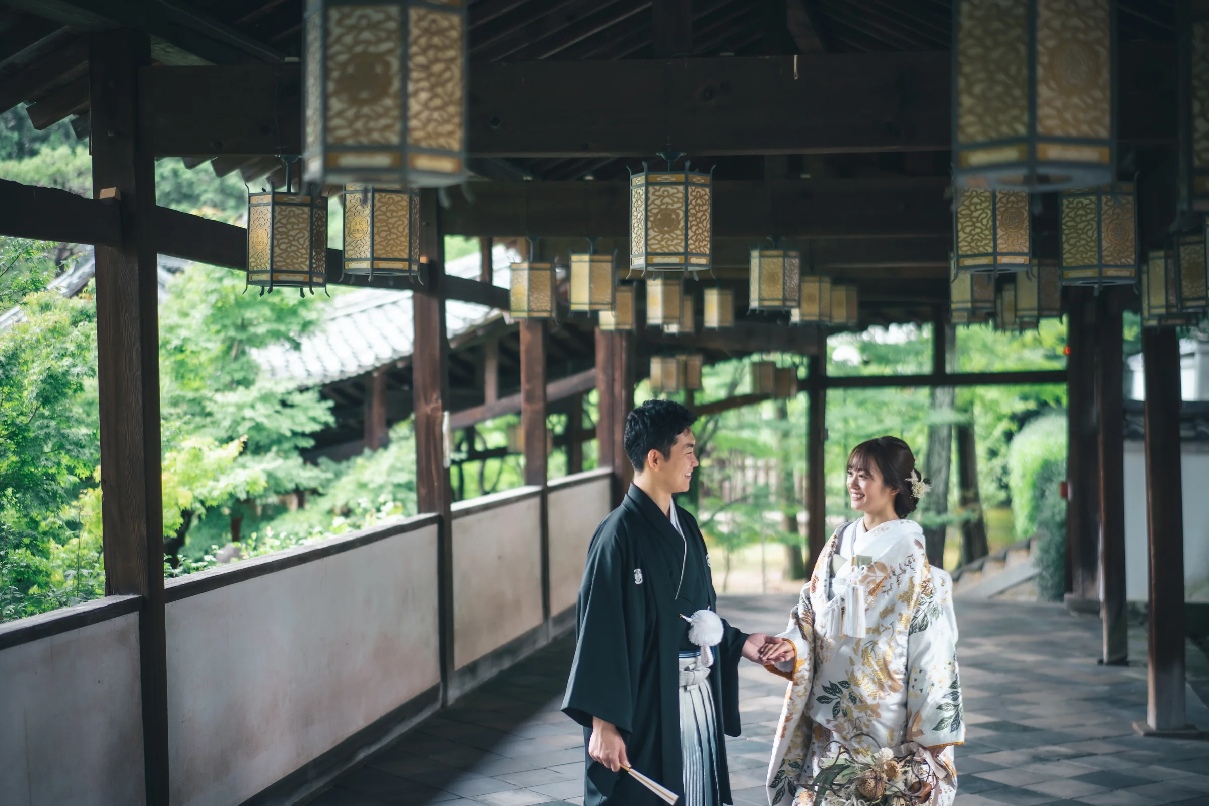 灯籠が連なる寺院の回廊で向き合う和装の二人