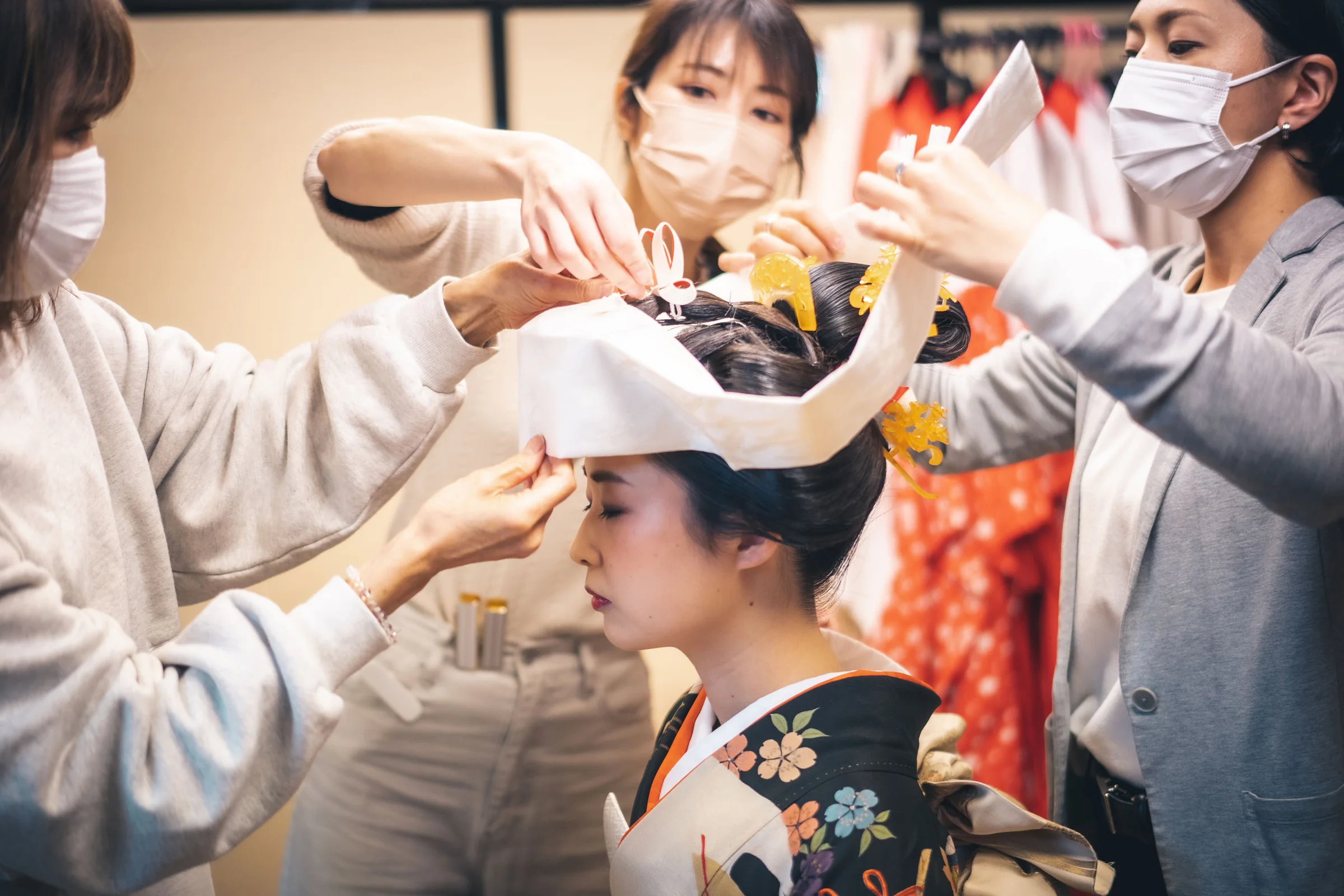 複数の美容スタッフの手で花嫁の伝統的な髪型と飾りを仕上げる様子